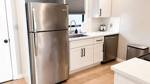 Une cuisine moderne dotée d’appareils électroménagers en acier inoxydable, de meubles blancs et d’un plancher en bois.