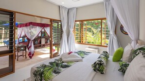 Une chambre avec un lit, une fenêtre avec des rideaux, un balcon avec une chaise et une vue sur la verdure.