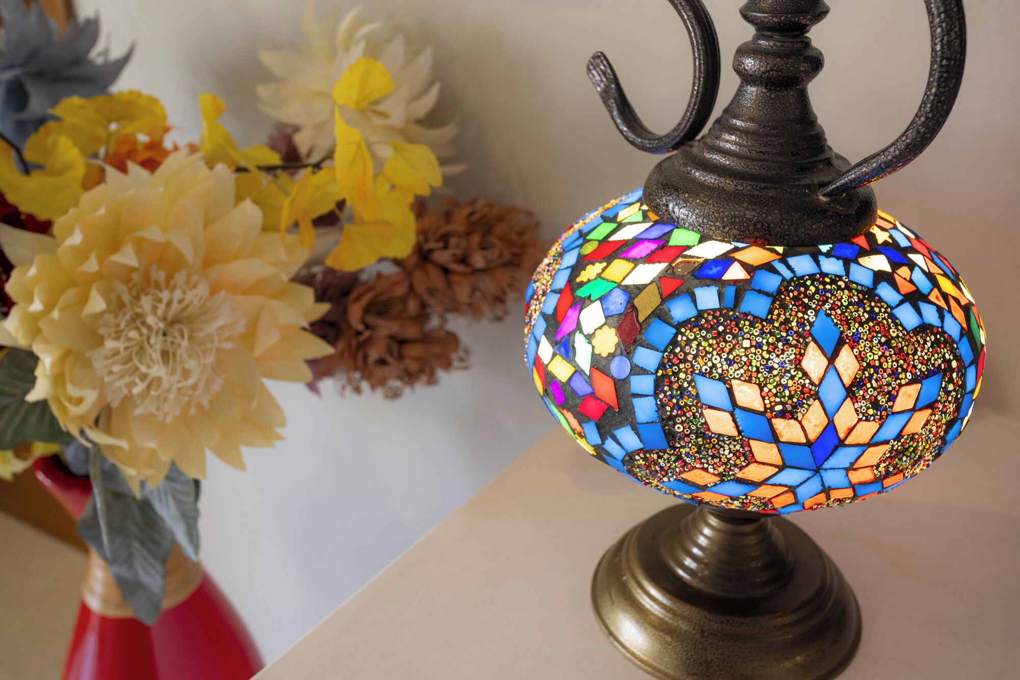 A mosaic lamp with a metal stand, placed on a table.