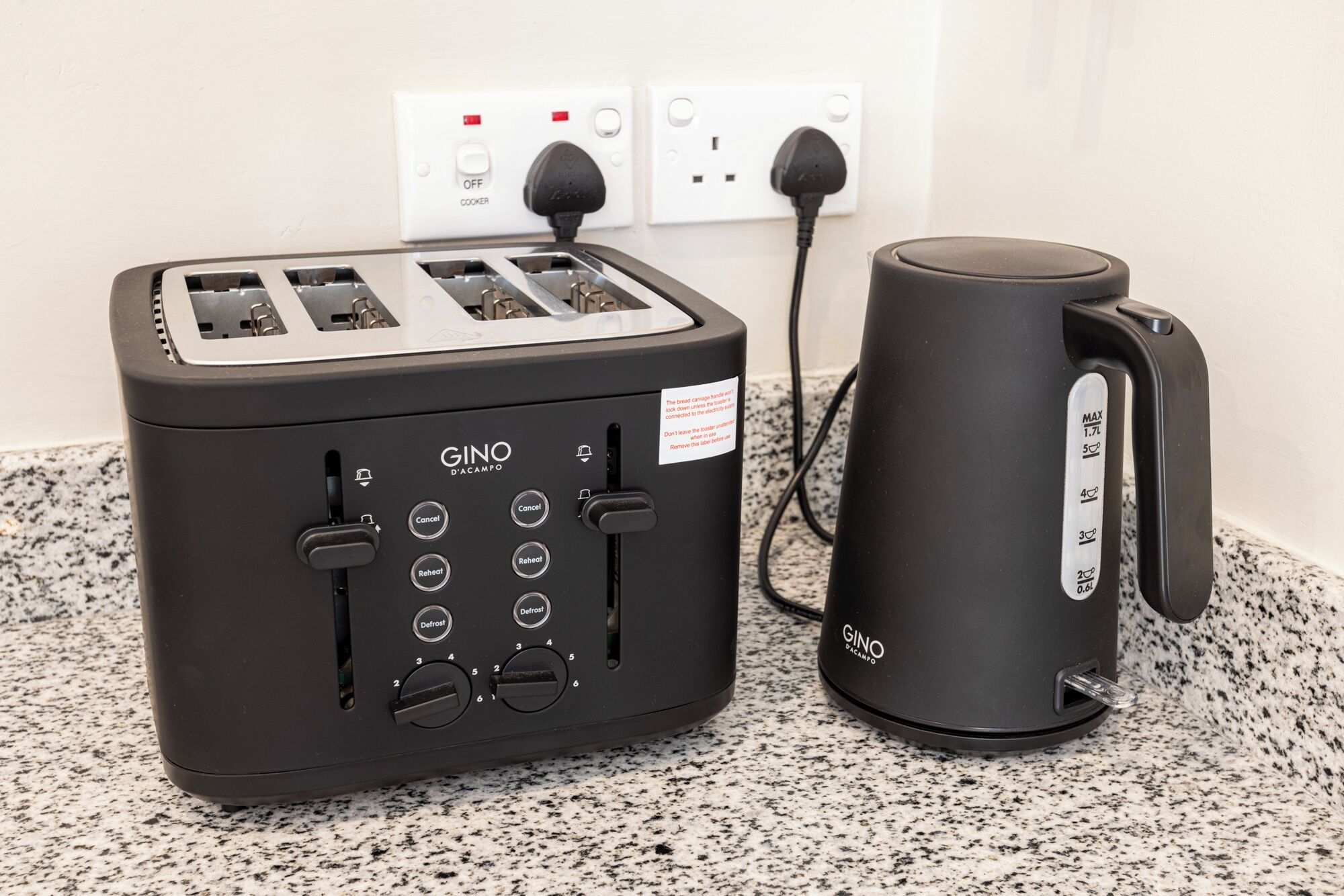 A kitchen with a black toaster and a black coffee maker on a granite countertop.