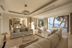 Amplia sala de estar con un sofá grande, una mesa de centro y un comedor con asientos al aire libre con vistas panorámicas.