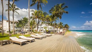 A beachside resort with a wooden deck, palm trees, and ocean views. - KITE BEACH HOTEL Two Story  2 /2 Oceanfront Apt with large Oceanfront Terrace (Puerto Plata Province)
