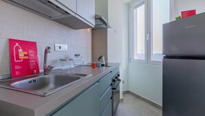 A modern kitchen with stainless steel appliances, a double sink, and a window providing natural light. - Valdellatorre Apartment by Wonderful Italy (Turin)