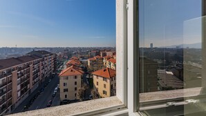 A view from a window overlooking a cityscape with multiple buildings, a clear sky, and a distant mountain range. - Valdellatorre Apartment by Wonderful Italy (Turin)