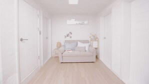 A hallway with a beige sofa, a small table, and a wall-mounted shelf with decorative items. - Wave House (Seoul)