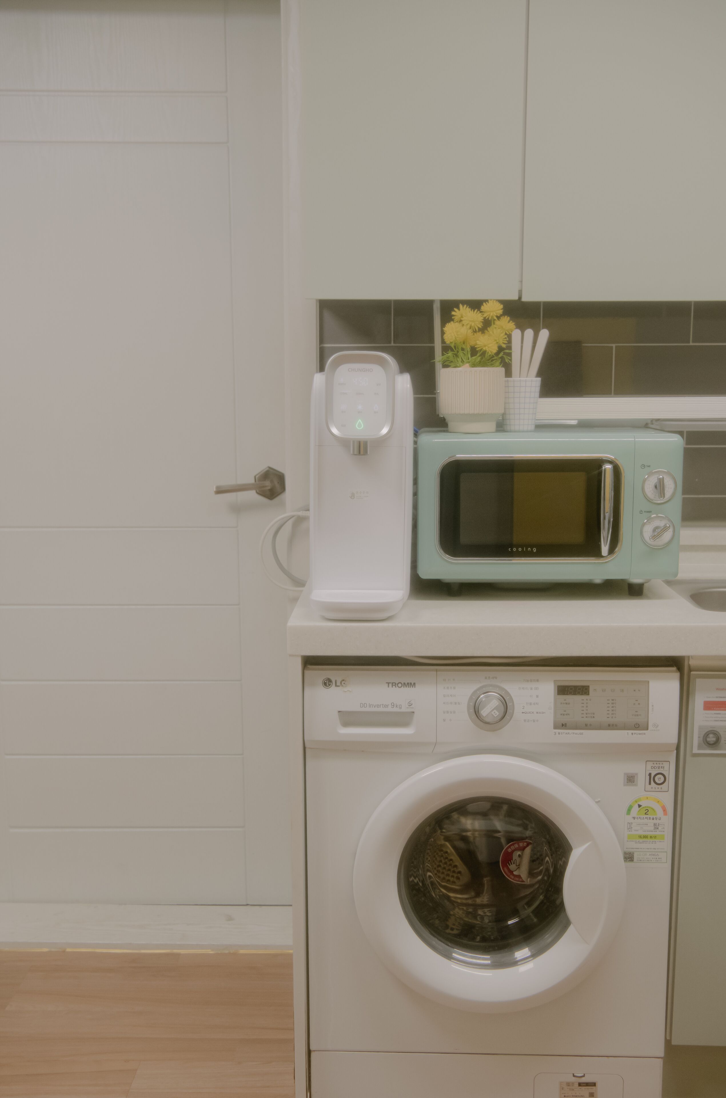 A compact kitchen with a washing machine, a microwave, and a toaster.