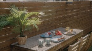 A wooden bench with a woven basket containing a plant, a picnic table with a plate of food, and a cup. - Wave House (Seoul)