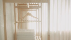 A wooden shelf unit with a hanging garment rack and folded towels. - Wave House (Seoul)