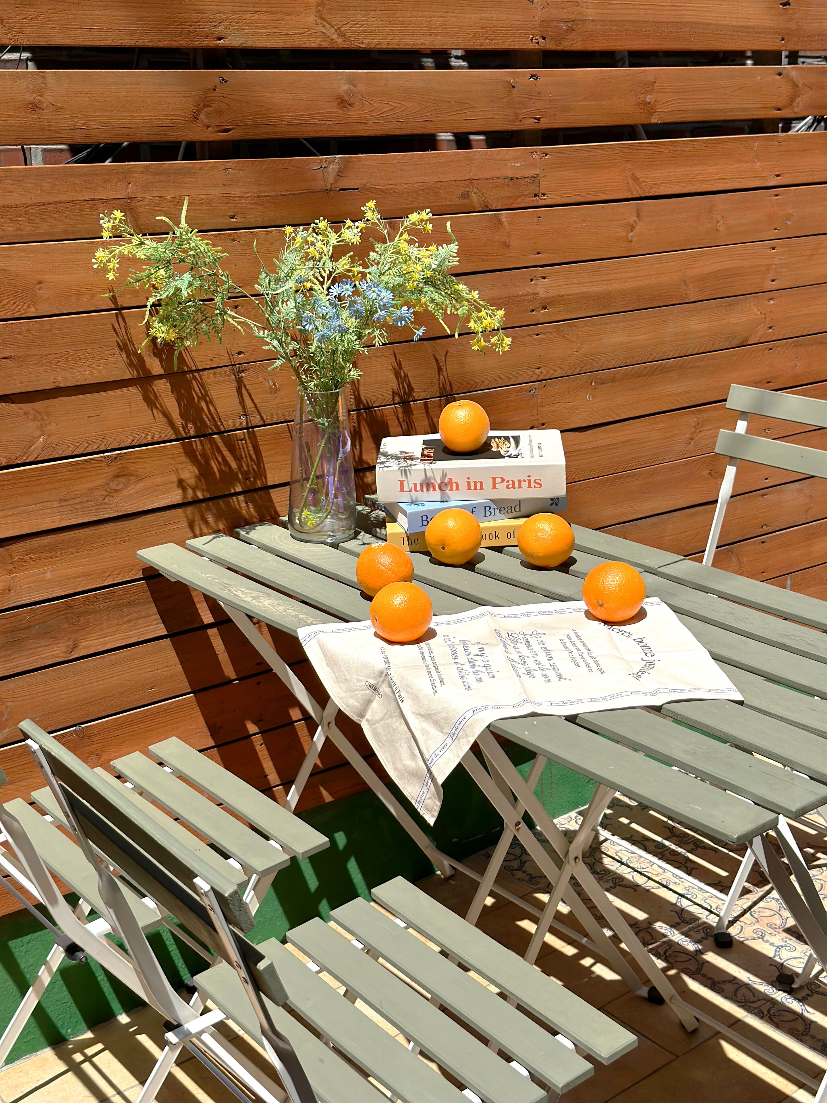 Ein Holztisch mit einer Speisekarte, Orangen und einer Blumenvase.