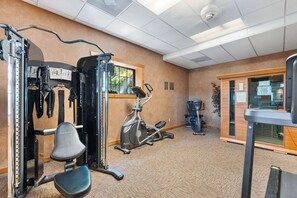 Ein Fitnessraum mit Trainingsgeräten, einem Fenster und einer Tür.