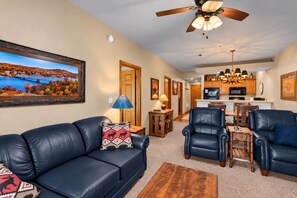 A living room with a blue leather sofa, a coffee table, and a dining area with a wooden table and chairs.
