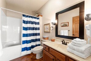 A bathroom with a bathtub, toilet, vanity with a mirror, and a shower curtain.