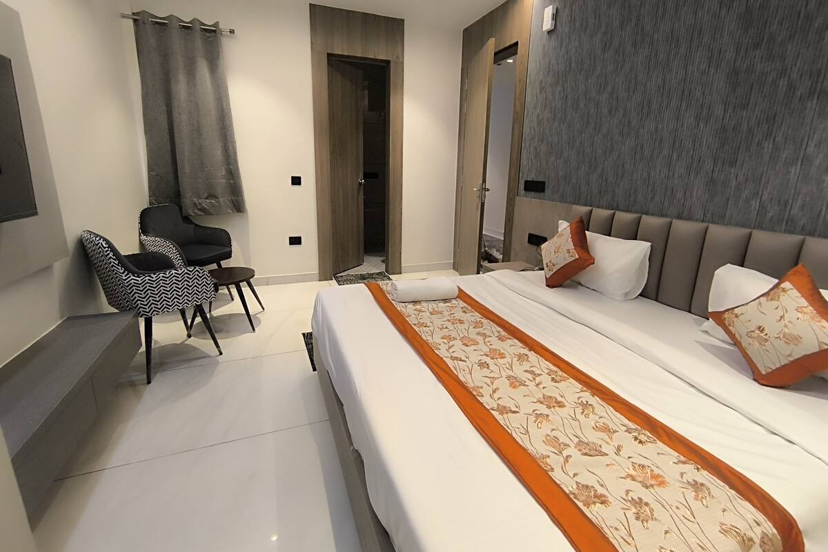 Une chambre d’hôtel moderne avec un grand lit, un petit bureau et une chaise.