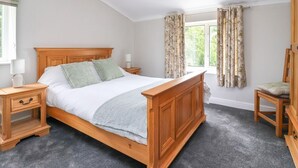 A bedroom with a wooden bed, two bedside tables, a nightstand, a chair, a wardrobe, and a window with curtains. - Bewholme (Driffield)