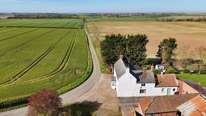A rural landscape with fields, a road, and a white building with a red-tiled roof. - Bewholme (Driffield)