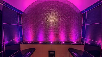 Bathroom features a mosaic wall design with two sinks and a dark floor.