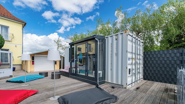 Eine moderne Terrassenanlage mit Glasverkleidung, Holzboden und einer roten und schwarzen Matte.
