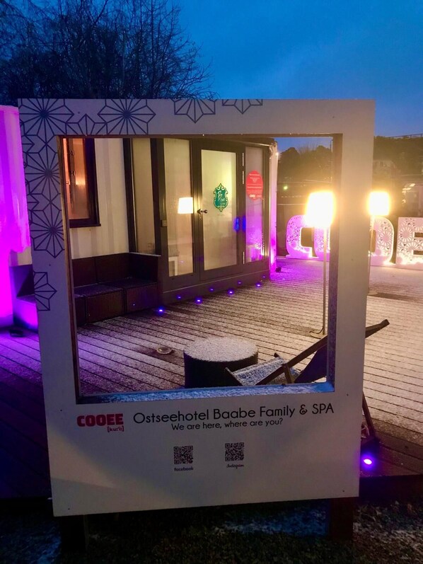 A sign for Ostseehotel Baabe Family & SPA with a view of the outdoor seating area and spa entrance.