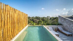 A rectangular pool with clear water, surrounded by a wooden fence and a stone wall. There are lounge chairs and a small table with a vase. - Chic 3-bedroom PENTHOUSE with private Pool & Sunset Terrace - Tulum (Tulum)