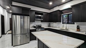 Una cocina moderna con armarios oscuros, electrodomésticos de acero inoxidable y encimera de mármol.