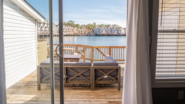 A balcony with a table and chairs, overlooking a body of water and buildings.