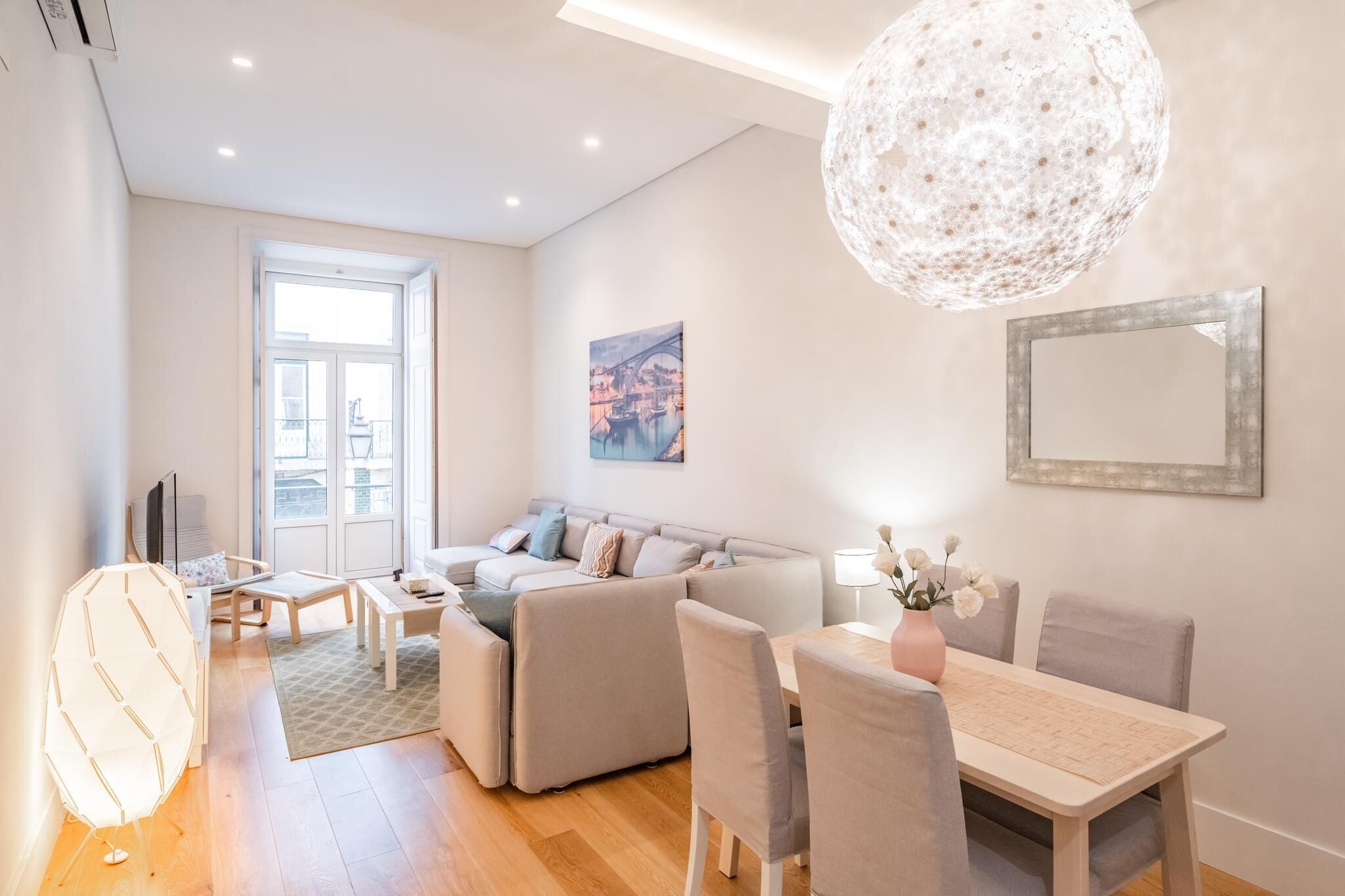 Ein modernes Wohnzimmer mit einer Couch, einem Esstisch und einem großen Fenster.