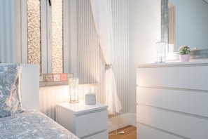 Cozy retreat with a neatly made bed, bedside table, and large mirror.