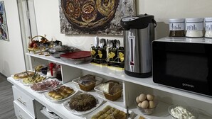 A buffet setup with various food items, a coffee maker, and decorative items on shelves. - Shams Art Hotel (Tashkent)