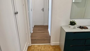 Un couloir doté d’un plancher en bois, de murs blancs et d’un meuble de couleur sombre, muni de tiroirs.