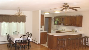 A spacious kitchen with wooden cabinets, a central island with stools, and a dining area with a table and chairs.