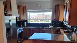 A modern kitchen with wooden cabinets, stainless steel appliances, and a large window offering a view of a garden. - Charming country cottage in lovely Santa Rosa on 8 acres (Santa Rosa)
