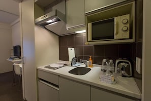 Compact kitchenette with microwave, oven, and sink, perfect for preparing meals.