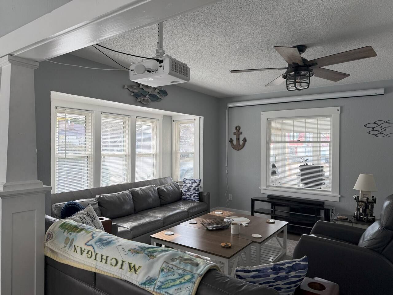 Un salon avec un canapé gris, une table basse et un ventilateur de plafond.