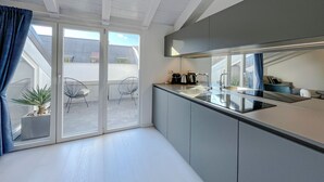 A modern kitchen with a large window, sliding doors to an outdoor area, and a built-in stove. - Pliny Suite 33 -N.7- (Milano)