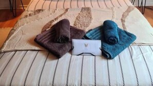 Ein ordentlich gemachtes Bett mit gestreifter Bettwäsche, zwei Kissen und einem gefalteten Handtuch.