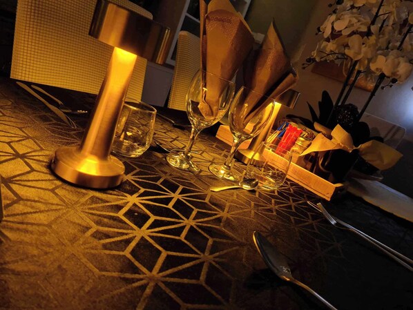 A table with geometric patterned tablecloth, a candle holder, wine glasses, and a box of napkins. - Les Epinettes (Crèvecœur-le-Grand)