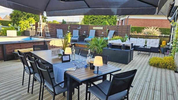 Eine Außenpatio mit Pool, einem Esstisch mit Stühlen und einer Lounge-Bereich mit Kissen und Tisch.