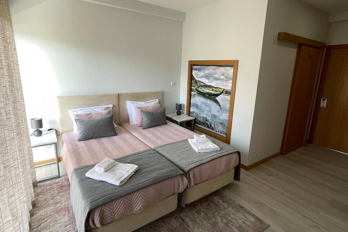 Un dormitorio moderno con una cama grande, una mesita de noche, un cuadro y una puerta de madera.
