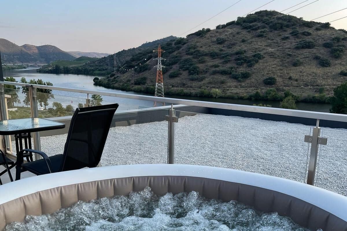 Un jacuzzi con vistas a un río y colinas.