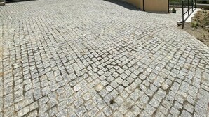 Une cour dallée avec un revêtement de pierre, un bâtiment doté d’un toit plat et un paysage montagneux en arrière-plan.
