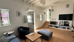 A living room with a sofa, a table, a TV, and a staircase leading to another room.