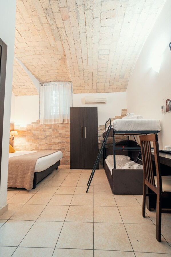 A compact room with a bunk bed, a desk, and a wardrobe.