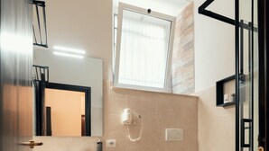A modern bathroom with a sink, bidet, toilet, and glass shower enclosure. - Saint Peter Loft (Rome)