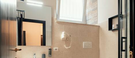 A modern bathroom with a sink, bidet, toilet, and glass shower enclosure.