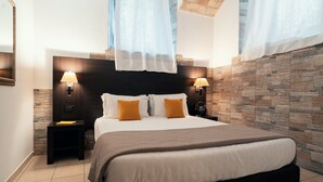 A modern bedroom with a large bed, two bedside tables with lamps, a stone accent wall, and a skylight. - Saint Peter Loft (Rome)
