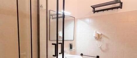 A bathroom with a glass-enclosed shower, a sink, a toilet, and a towel rack.