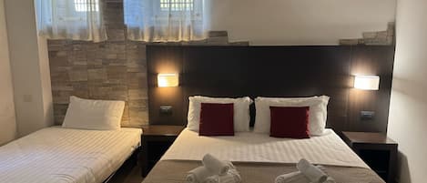 Klassieke driepersoonskamer | Een minibar met enkele gratis items, een bureau, een laptopwerkplek