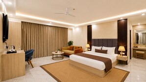 A modern hotel room with a large bed, a desk, a chair, a TV, and a ceiling fan. - Hotel West End Mahipalpur Delhi IGI (New Delhi)