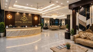 A hotel lobby with a reception desk, seating area, and a chandelier.