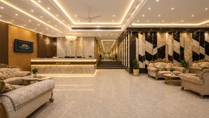 A hotel reception area with a marble reception desk, plush seating, and a staircase leading to upper floors. - Hotel West End Mahipalpur Delhi IGI (New Delhi)